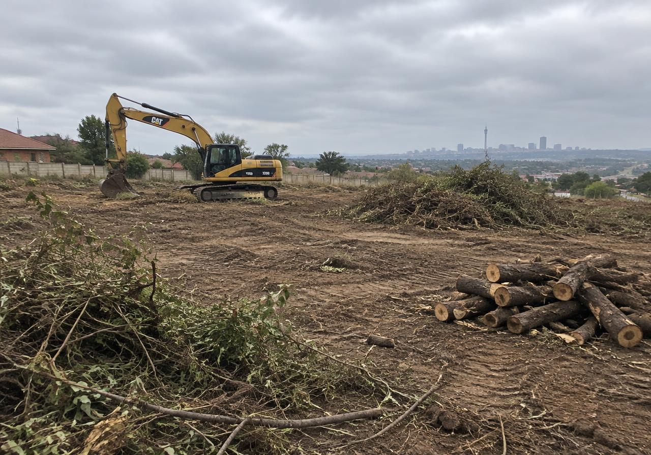 Cleared site with excavator and stacked logs